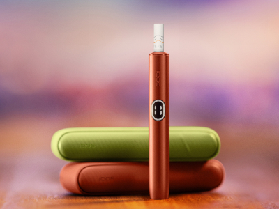 أيدي تحمل جهاز IQOS ILUMA PRIME بلون أخضر يشمي.